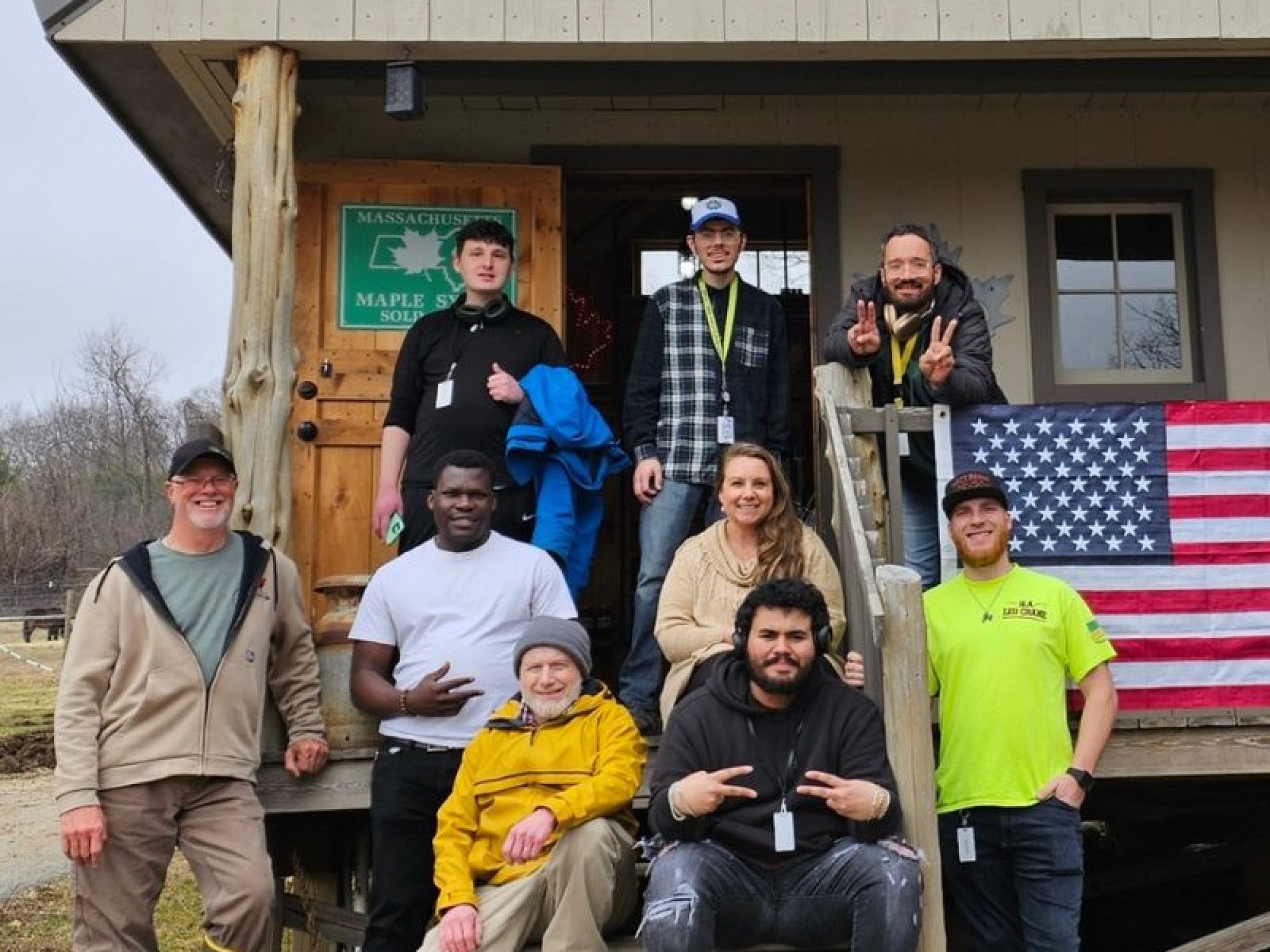 Venture Community Services staff and program participants posing outside a rustic program building