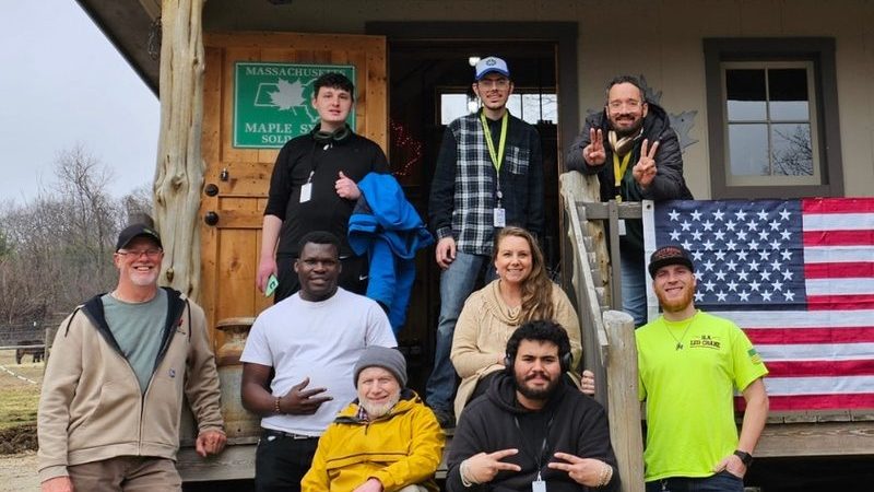 Venture Community Services staff and program participants posing outside a rustic program building