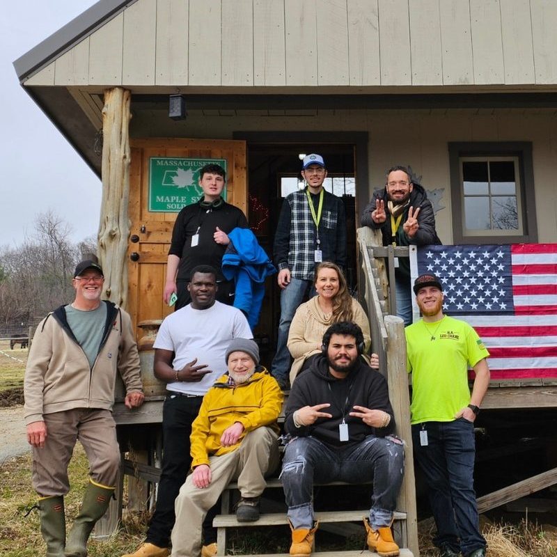 Venture Community Services staff and program participants posing outside a rustic program building