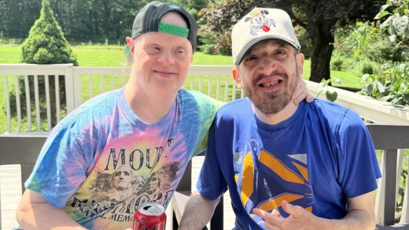 Two program participants smiling together outdoors on a deck