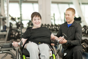 Disabled female in wheelchair exercising with trainer.